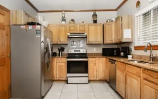 Arvada-gallery-14 Modern kitchen with stainless steel appliances, wooden cabinets, granite countertops, and various small kitchen items arranged on counters and cabinets.