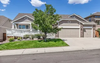 Single-story beige house in Castle Rock with a front yard, tree, and attached three-car garage, viewed from the street on a sunny day—an inviting option for those seeking Memory Care or TBI Support in a comfortable setting.