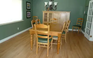 Littleton-gallery-5 A dining room with a wooden table, six matching chairs, a glass-front cabinet, green walls, and wood flooring.